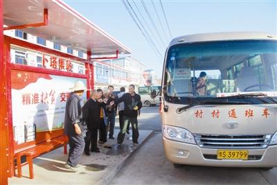 10月13日上午,在潢川县卜塔集镇候车站亭,村民正高兴地乘坐村村通班车
